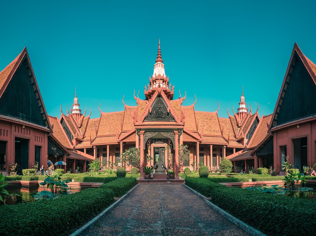 The ornate Khmer architecture of the Royal Palace Throne Hall against a bright blue sky.